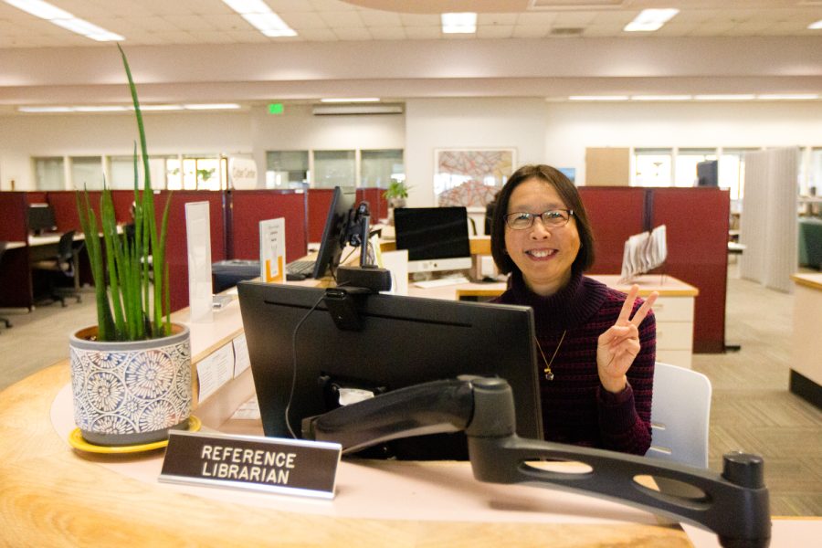 Sally Chuah, the Library Chair, smiles while holding up a peace sign on March 2 at her desk in The Luria Library in Santa Barbara, Calif. Chuah wants to break stereotypical views of librarians by being welcoming, and creating an engaging space for students.