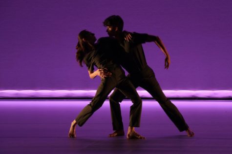 Katie Evans (left) and Adrián González (right) join in an embrace during the piece Cui Bono? during the 2023 Dance Collective on April 15 at the Garvin Theatre in Santa Barbara, Calif. The purple lighting accentuates the dancers dark costumes as they sway together.