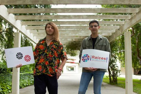 From the left, Ziv Taylor holds a Raíces logo poster next to fellow City College graphic designer, Adrian Rodriguez, who also displays the Raíces branding. The two designers are standing outside of the Student Services building at City College in Santa Barbara, Calif. Taylor and Rodriguez both designed the logo for the Raíces program at City College.