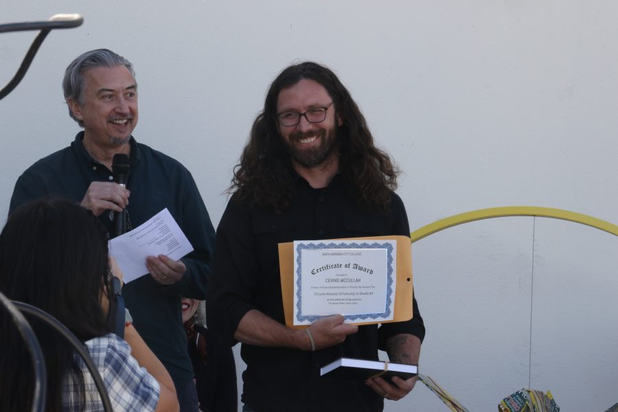 John Connely (left) gleems while presenting Cenvis Mccullahs Eli Luria Honorary Scholarship in Studio Art at the 2023 Student Exhibition on Thursday, April 20 in Santa Barbara, Calif. The scholarship was amounted at $5,000.