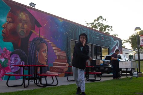 Josiah Megzs, 9, plays football in front of the new mural lining the walls of Umoja on Wednesday, Feb. 15 at City College.