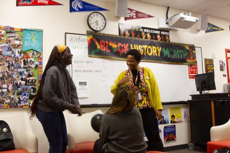 Surrounded by posters, banners, and photographs, Umoja Student Program Advisor Lelia Richardson laughs with students in the Umoja program during their Black History 365 event on Wednesday, Feb. 15, 2023 at the Center of Equity and Social Justice at City College.