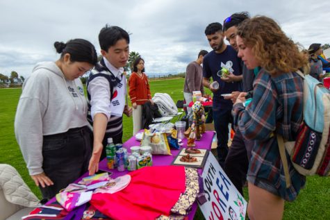 From left, Vella Nam and Chanhee Kang display various traditional and contemporary South Korean idols, clothing, and snacks on Thursday, May 4 at their booth in Santa Barbara, Calif. According to Nam and Kang, they chose to offer savory snacks, such as honey twists and garlic chips, instead of native South Korean fruits, which would have spoiled.