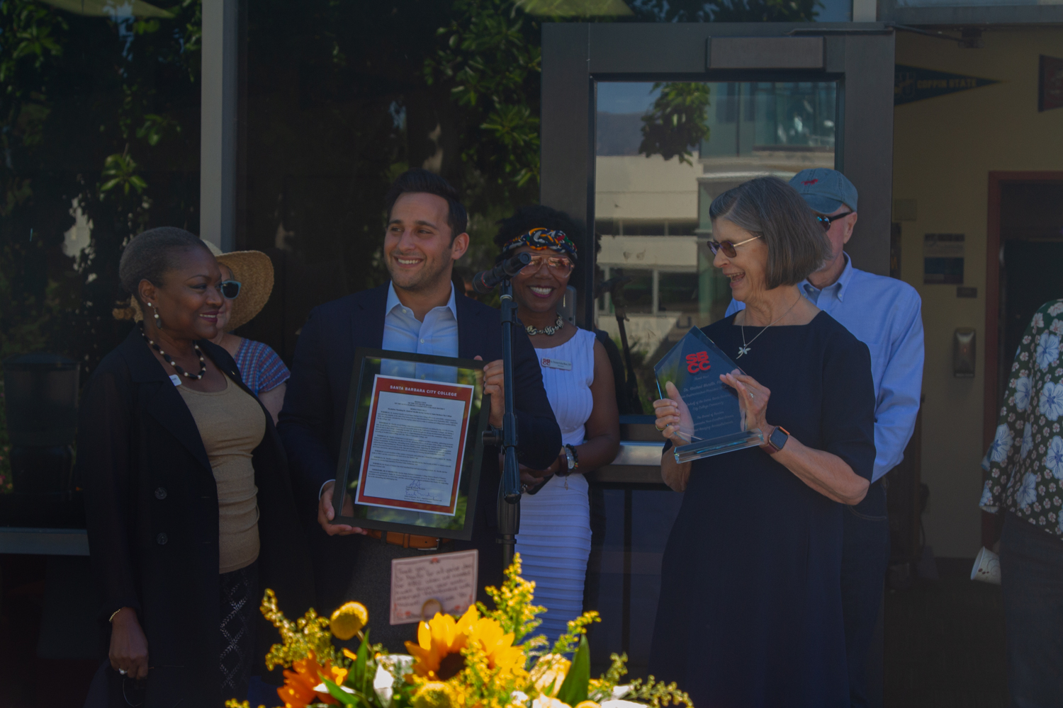 From left Trustee Anna Everett and Jonathan Abboud, president of the Board of Trustees, present Kindred Murillo with the framed resolution in front of the gathering for Murillos retirement event on Aug. 30 at the Campus Center Umoja Mural at City College in Santa Barbara, Calif. 