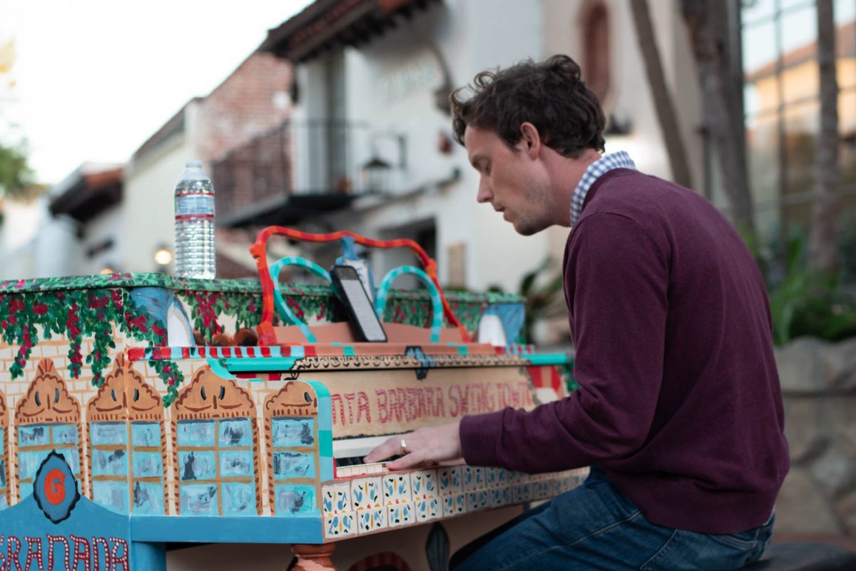 Cody Sargent sings quietly while playing a piano on Oct. 10 at the corner of Figueroa and State Streets in Santa Barbara, Calif. This piano was painted by Santa Barbara artist Brett Renee.