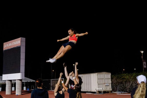 Acelyn Sutton rotates her body as her teammates prepare to catch her in a cradle. Much of the cheer team's Sept. 28 practice was dedicated to stunting at City College's La Playa stadium in Santa Barbara, Calif. (Anthony Zell)