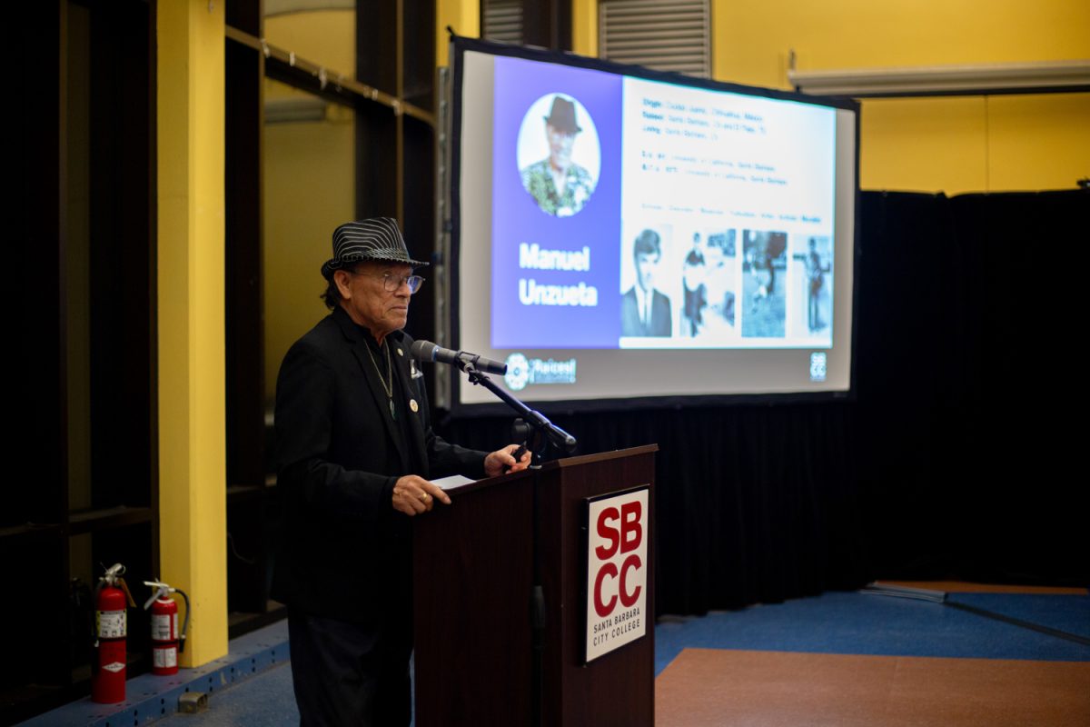 Manuel Unzueta stands at the podium during his presentation for the Plática about “Metamorphosis of Reality, a mural he painted on the Campus Center on Thursday, Oct. 26 in Santa Barbara, Calif. “Metamorphosis of Reality came to life in 1976 by Unzueta and SBCC students. 